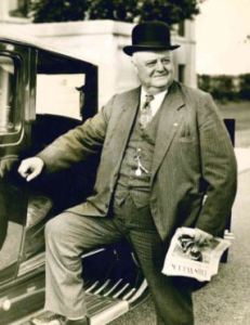 A.E. Staley standing next to a car, black and white