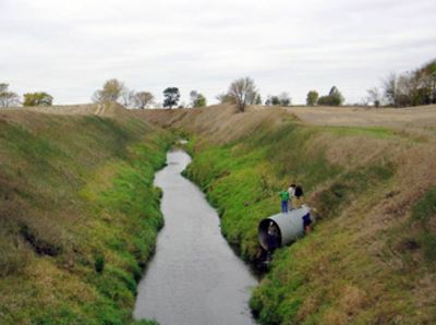 A tile main flows deep in the ground with large banks on either side