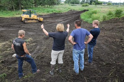 Four people standing in a bulldozed area