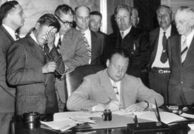 Secretary of the Interior Julius Krug signs the Pick-Sloan Act as tribal leader George Gillette sobs in grief.