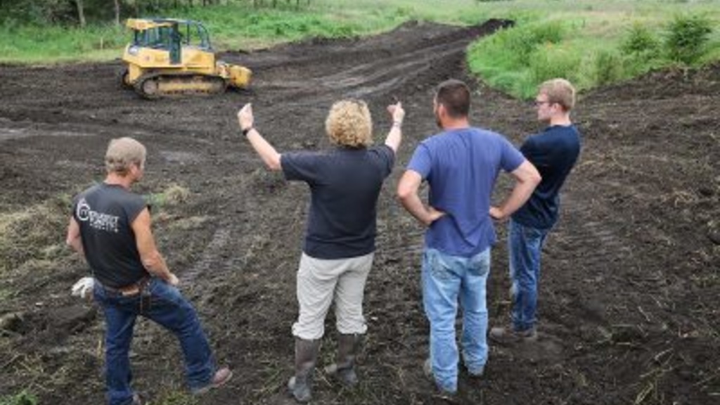 Four people standing in a bulldozed area