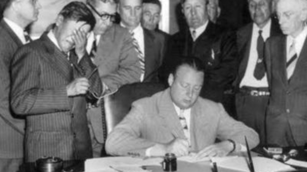 Secretary of the Interior Julius Krug signs the Pick-Sloan Act as tribal leader George Gillette sobs in grief.